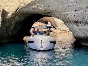 A sleek boat navigates through a stunning rock arch, showcasing a picturesque scene of exploration and adventure on the water.