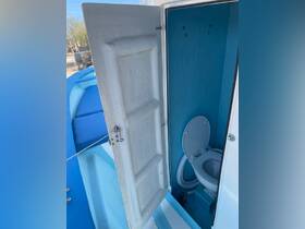 Interior view of a boat's bathroom featuring a clean toilet and bright blue walls, showcasing the essential amenities for comfort on the water.