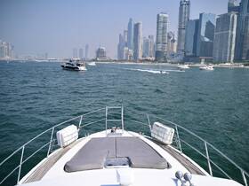 A stunning view from the bow of a yacht cruising through clear waters, with a backdrop of modern skyscrapers in the distance, showcasing the vibrant atmosphere of a bustling marina.