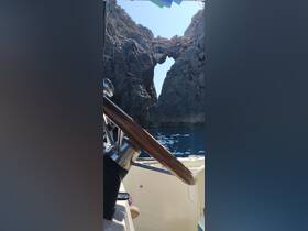 A stunning view of a natural rock arch from the helm of a boat, showcasing the breathtaking coastline and crystal-clear waters — perfect for adventure seekers exploring hidden gems.