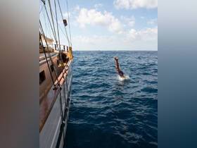 A person dives into the sparkling ocean from the side of a boat, capturing the thrill of water activities and the joy of summer adventures on the sea.