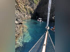 A stunning view of a secluded cave with crystal-clear waters, featuring boats and guests enjoying the picturesque surroundings — perfect for exploration and adventure.