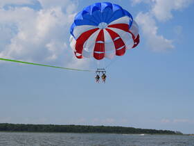 Two adventurers enjoy an exhilarating parasailing experience over calm waters, capturing the thrill of water sports and scenic views.