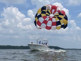 A thrilling parasailing adventure above the water, showcasing the excitement of on-water activities with a boat in motion.