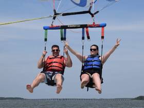 A couple enjoys an exhilarating parasailing adventure over the water, capturing the thrill of summer fun and adventure sports.