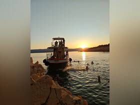 A lively group enjoys a sunset swim around the boat 'Vojga' — a perfect setting for summer fun and aquatic adventures.