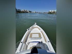 A clear view of the front of a speedboat cruising through calm waters, showcasing the vessel's sleek design against a backdrop of coastal buildings.
