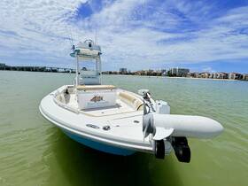 A sleek speedboat named 'Knot Dressing' is docked in calm waters, showcasing its modern design against a backdrop of coastal buildings.