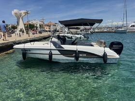 A sleek speedboat docked in clear waters, showcasing its modern design and features, with a scenic waterfront in the background.