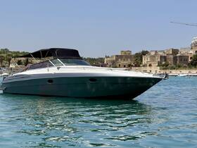 A sleek speedboat anchored in calm waters, showcasing its elegant design against a picturesque coastal backdrop.