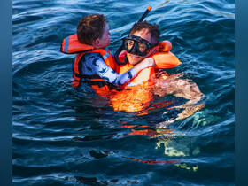A joyful moment as a father and son enjoy snorkeling together in clear waters, showcasing a memorable family adventure in the ocean.
