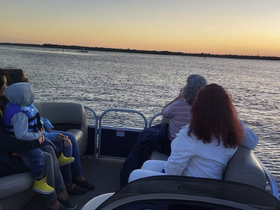 A family enjoys a serene sunset cruise on a pontoon boat, capturing the beauty of the moment together on the water.