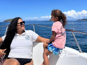 A joyful moment on the water as a woman and a young girl share smiles aboard a boat, enjoying the beautiful ocean scenery.