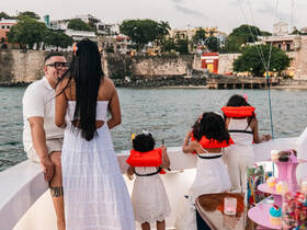 A joyful family enjoys a scenic boat ride, with children wearing life jackets and a couple sharing a moment, perfect for memorable celebrations on the water.