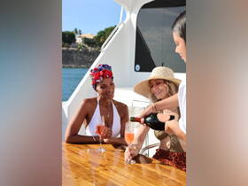 Two friends enjoy a celebratory moment aboard a yacht, sipping cocktails and sharing laughter under the sun — perfect for unforgettable gatherings on the water.