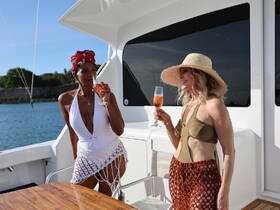Two friends enjoy cocktails on the deck of a luxurious yacht, capturing the essence of a perfect day on the water.
