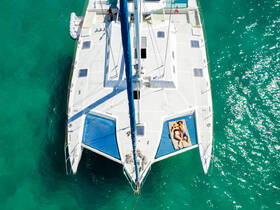 A couple relaxes on the netting of a catamaran, soaking up the sun against a backdrop of stunning turquoise waters — an ideal scene for romantic getaways or leisure sailing.