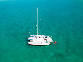A stunning aerial view of a catamaran anchored in crystal-clear turquoise waters, perfect for exploring tropical destinations.