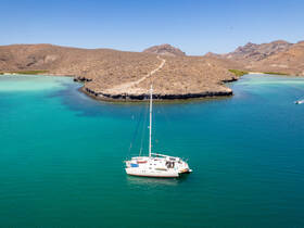 A stunning aerial view of a sailboat anchored in crystal-clear turquoise waters, surrounded by rugged coastline and natural beauty — perfect for exploring secluded bays.