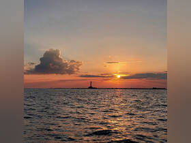 A stunning sunset over the water, featuring a lighthouse silhouette against a colorful sky — a perfect backdrop for evening boat trips.