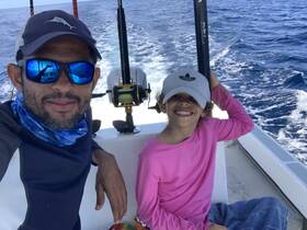 A joyful moment captured on a fishing trip, featuring a smiling adult and child aboard a boat, showcasing the fun of family time on the water.