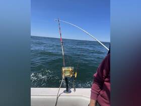 A fishing rod and reel are set up on a boat, ready for an exciting day of fishing on the open water.