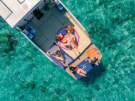 A group of friends relaxes on a boat, sunbathing and enjoying the clear turquoise waters — the perfect setting for a summer getaway.