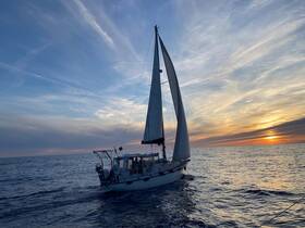 A beautiful sailboat glides through the water at sunset, showcasing the serene beauty of a sailing experience on the open sea.