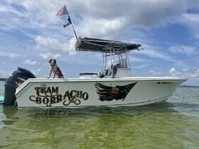 A sleek speedboat named 'Team Borracho' anchored in clear waters, featuring a dog standing proudly on the bow — perfect for fun days on the water.