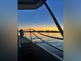 A serene view of a boat at sunset, showcasing the tranquil waters and the silhouette of trees in the background — perfect for peaceful evening cruises.