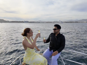A couple toasts with champagne on the bow of a yacht, enjoying a romantic moment on the water — perfect for sunset cruises and special celebrations.
