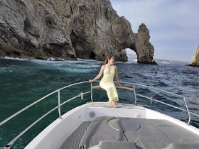 A woman enjoys the stunning views from the bow of a boat near the iconic rock formations of Cabo San Lucas, creating a perfect backdrop for memorable adventures on the water.