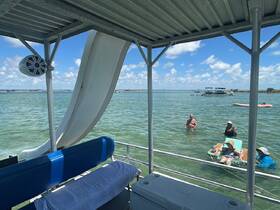 A lively group enjoys a day on the water, swimming and relaxing around a pontoon boat, showcasing the perfect summer getaway.