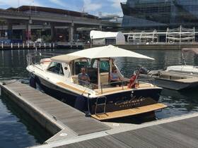 Two guests relax aboard the yacht 'Salute' while docked, showcasing a perfect spot for leisure in a vibrant marina setting.
