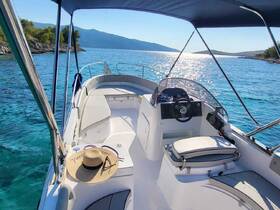 A bright and inviting view of the helm area inside a boat, featuring comfortable seating and a stylish sun hat, perfect for enjoying a day on the water.