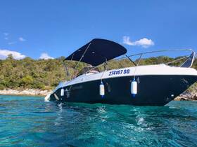 A sleek Marinello boat anchored in clear turquoise waters, showcasing its elegant design against a lush green backdrop — perfect for a day of exploration on the water.