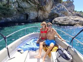 A couple enjoys a sunny day on a boat, surrounded by stunning rocky scenery and crystal-clear waters — perfect for a romantic getaway or adventure.