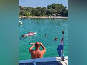 A lively group enjoys a sunny day in the water, with some swimming and others kayaking, creating a perfect beach day experience.