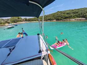 A lively group enjoys a sunny day on the water, swimming and paddleboarding in crystal-clear turquoise waters, perfect for summer adventures.