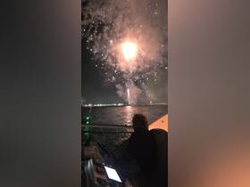 A stunning view of fireworks lighting up the night sky from aboard a boat, creating a festive atmosphere perfect for celebrations on the water.
