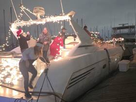 A festive group decorates a boat with holiday lights, capturing the spirit of celebration on the water. Perfect for holiday gatherings and boat parties.