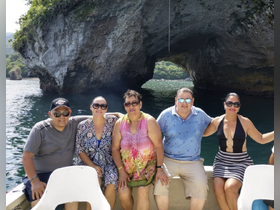 A cheerful group poses for a photo on a boat with stunning rock formations in the background, capturing a memorable moment during their aquatic adventure.