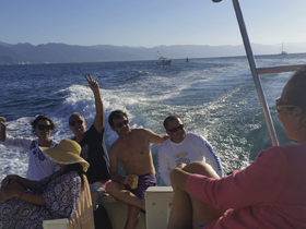 A lively group enjoys a fun day on the water, celebrating and making memories aboard a boat with stunning views in the background.
