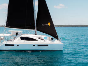 A sleek catamaran with a striking black sail glides through clear turquoise waters, showcasing its elegant design and perfect for sailing adventures.