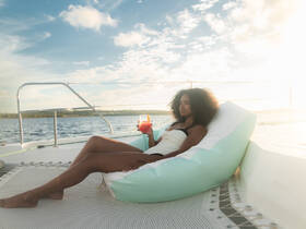 A woman relaxes on a yacht with a cocktail in hand, enjoying the serene sunset views — the perfect setting for a luxurious getaway on the water.