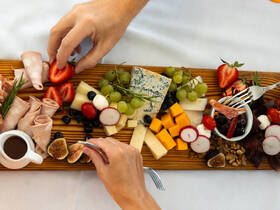 A beautifully arranged charcuterie board featuring a variety of cheeses, meats, and fresh fruits, perfect for enjoying onboard during a relaxing day at sea.