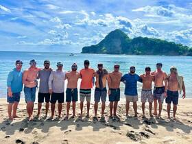 A group of friends poses together on the beach, enjoying a sunny day by the water — perfect for memorable beach outings and celebrations.