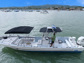 A center console boat named 'Gabriela' is docked, with a captain at the helm, showcasing a serene harbor setting.