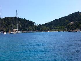 A scenic view of several yachts anchored in a tranquil bay, surrounded by lush greenery and clear blue waters, perfect for a relaxing day on the water.