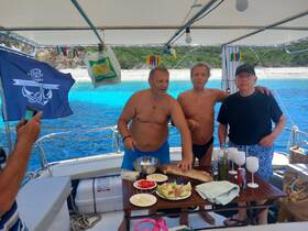 A lively group enjoys a boat party, preparing snacks and drinks while surrounded by stunning blue waters — perfect for a memorable day at sea.